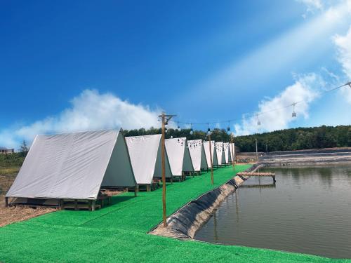 Une rangée de tentes bordées d'une nappe d'eau dans l'établissement SAY Camp Forest, à Cần Giờ