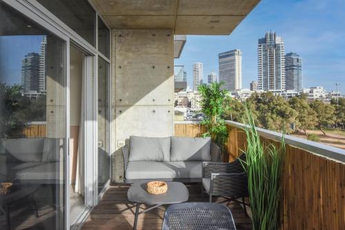 a balcony with a couch and chairs and a table at Modern 3-BR near Beach Club by HolyGuest in Tel Aviv