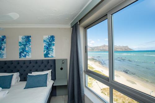 a bedroom with a bed and a view of the beach at Ocean Breeze Hotel in Strand