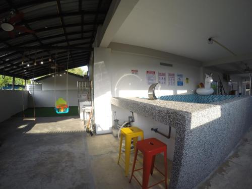 cocina con encimera con fregadero y 2 taburetes en CoCo Fun House Kemaman with Pool and Bathtub, en Kampong Gong Pauh