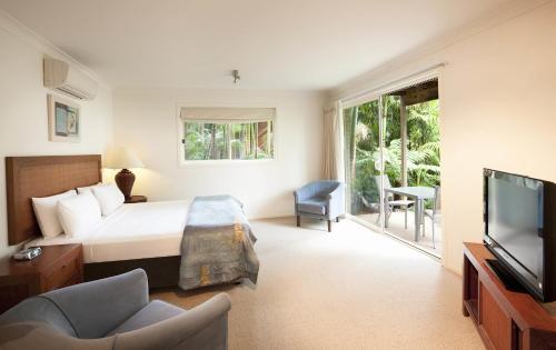 Habitación de hotel con cama y TV en BreakFree Aanuka Beach Resort, en Coffs Harbour