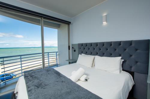 a bedroom with a large bed and a large window at Ocean Breeze Hotel in Strand