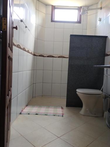 a bathroom with a toilet and a window at Pousada Axe in Cumuruxatiba