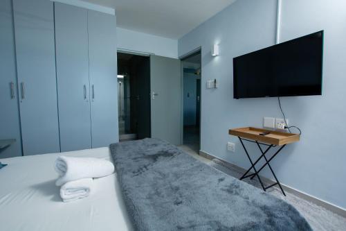 a bedroom with a bed with a tv on the wall at Ocean Breeze Hotel in Strand