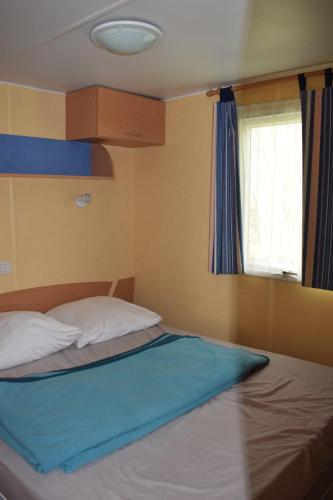 une chambre avec un lit avec une couverture bleue et une fenêtre dans l'établissement Camping du Creulet, à Crouay