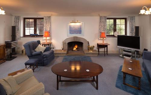 a living room with a fireplace with a couch and a table at Tigh Chailein in Tarbert