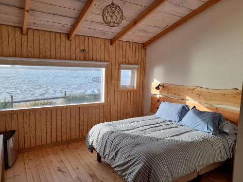 ein Schlafzimmer mit einem Bett und einem großen Fenster in der Unterkunft Portal de la Patagonia Austral in Puerto Montt