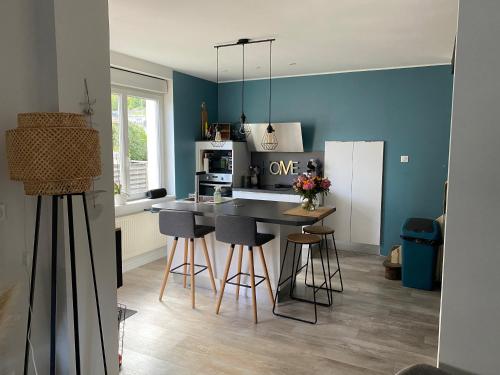uma cozinha com paredes azuis e uma ilha de cozinha com bancos em Maison de ville em Bort-les-Orgues