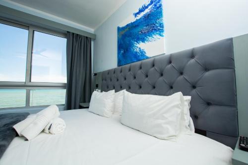 a bedroom with a large white bed with a large window at Ocean Breeze Hotel in Strand
