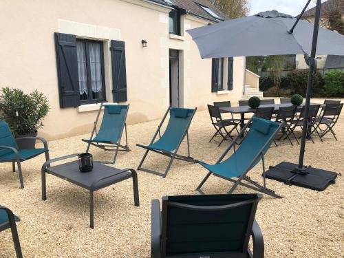 a group of chairs and a table with an umbrella at Gîte La Patouille in Amboise