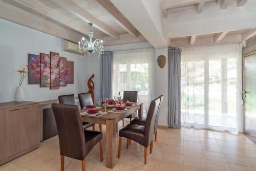 a dining room with a wooden table and chairs at Posidonia Luxury Villas Kolympia in Kolimbia