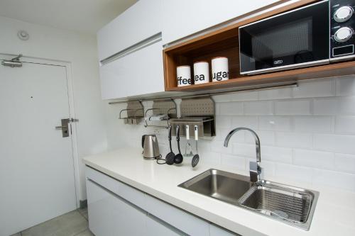 a kitchen with a sink and a microwave at Ocean Breeze Hotel in Strand