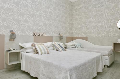 a bedroom with two beds with white sheets at Hotel Flora in Cattolica