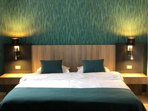 a bedroom with a large bed with two green pillows at Pensiunea Lido in Piatra Neamţ