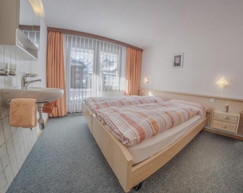 a bedroom with a bed and a sink and a window at Apartments Bergrose in Saas-Fee
