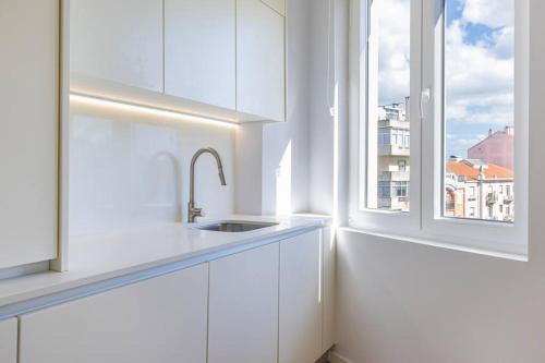 a white kitchen with a sink and a window at Monteverde VI by Innkeeper in Lisbon
