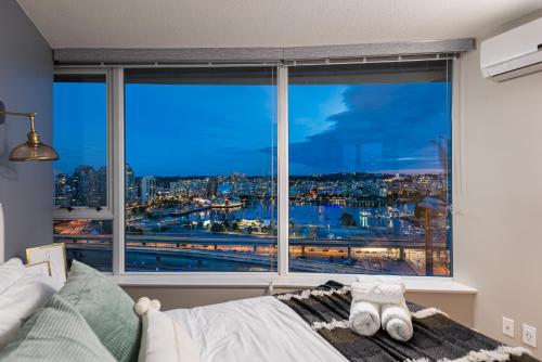 a bedroom with a large window with a view of a city at Vancouver Nest Downtown 2BR near Rogers Arena in Vancouver