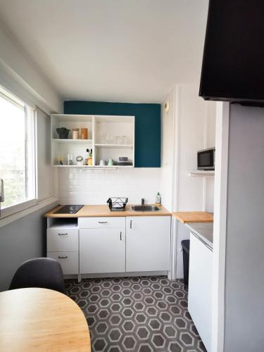 une petite cuisine avec des placards blancs et une table dans l'établissement Cosy 30m in the heart of Villeurbanne, à Villeurbanne