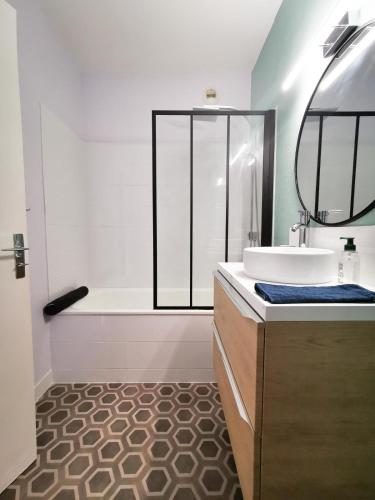 La salle de bains est pourvue d'une baignoire, d'un lavabo et d'un miroir. dans l'établissement Cosy 30m in the heart of Villeurbanne, à Villeurbanne