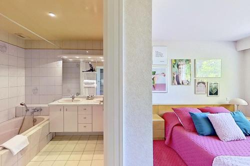 a bathroom with a pink couch and a bath tub at Les Jardins de la Muse, piscine couverte, spa et fitness in Basse-Goulaine