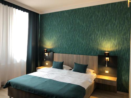 a bedroom with a large bed and a green wall at Pensiunea Lido in Piatra Neamţ