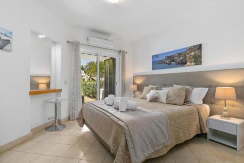 ein Schlafzimmer mit einem großen Bett und einem Fenster in der Unterkunft Balaia Golf Poolside Retreat - Superior 2 bed villa in Albufeira