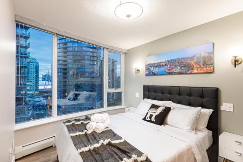 a bedroom with a bed and a large window at Condo in Downtown Vancouver - Near Rogers Arena in Vancouver