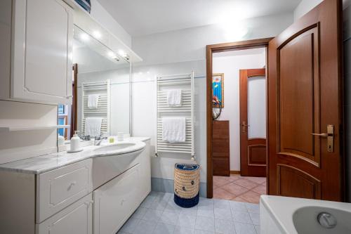 a white bathroom with a sink and a mirror at Apartment with bicycle storage in Dongo - Larihome A24 in Dongo