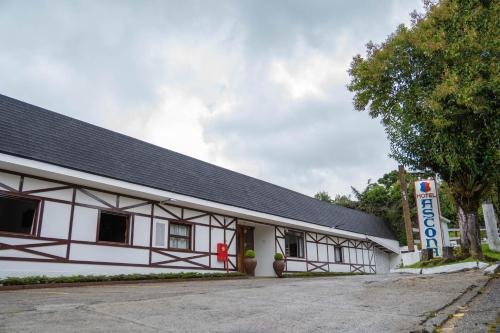 a white building with a black roof at Hotel Ascona in Campos do Jordão