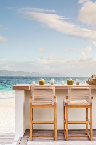 two chairs sitting at a table on the beach at Aurora Anguilla Resort & Golf Club in Rendezvous Beach