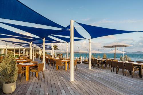 a restaurant with tables and umbrellas on a wooden deck at Aurora Anguilla Resort & Golf Club in Rendezvous Beach