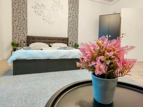 um quarto com uma cama e uma mesa com um vaso de flores em 22 LOOP Apartment em Brasov