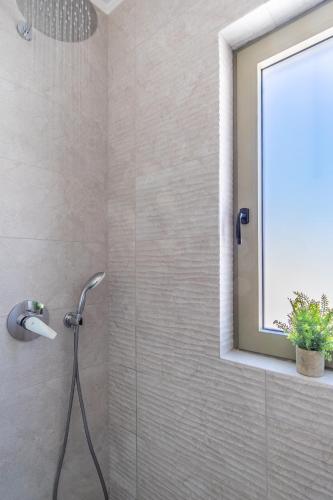 a shower in a bathroom with a window at Villa Kalligoni in Kalligónion