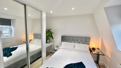 a small bedroom with a bed and a mirror at The Loft Queens Park in London