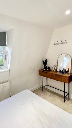 - une chambre avec un lit et un bureau avec un miroir dans l'établissement The Loft Queens Park, à Londres