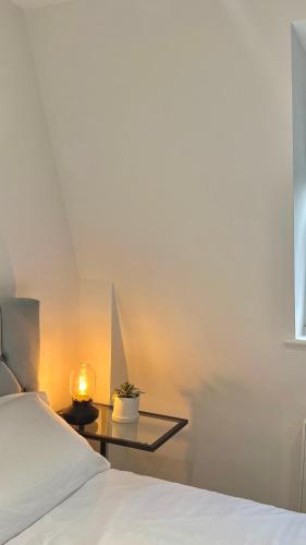 een slaapkamer met een bed en een tafel met een lamp bij The Loft Queens Park in Londen