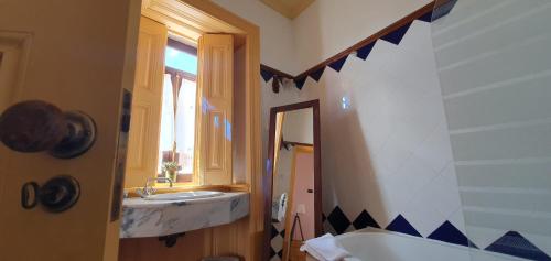 W łazience znajduje się wanna, umywalka i lustro. w obiekcie Casa do Fundo - Sustainable & Ecotourism w mieście Seia