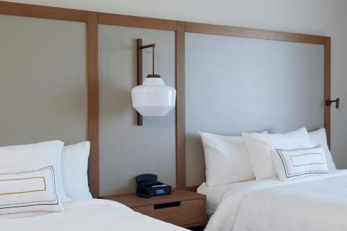 a bedroom with two beds and a clock on a night stand at Fairfield Inn & Suites by Marriott Riverside Moreno Valley in Moreno Valley
