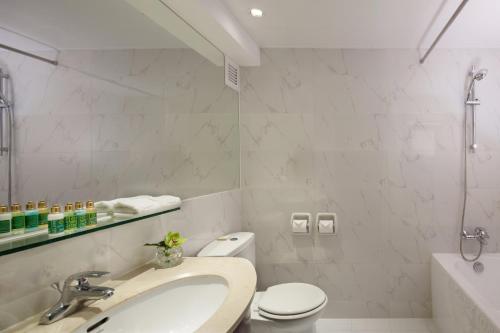 Baño blanco con lavabo y aseo en Beijing Landmark Towers, en Beijing