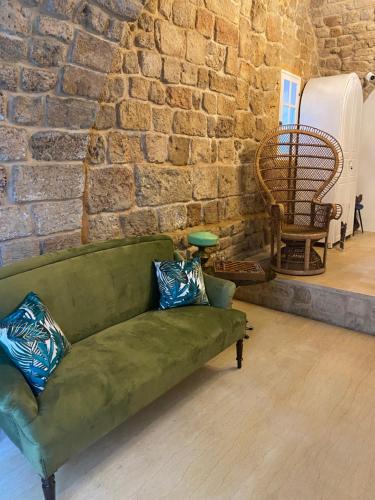 a green couch in a room with a brick wall at Dar Alice in Soûr