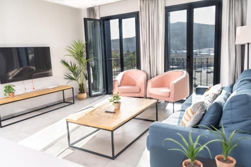 sala de estar con sofá azul y sillas rosas en Apartamentos Turísticos Puerta Real, en Cartagena