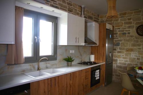 cocina con armarios de madera, fregadero y ventana en Private Villa Freedom, en Moírai