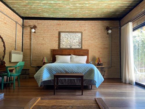 a bedroom with a bed and a brick wall at LA PIANTA - Uma experiência na Villa de Monte Verde in Monte Verde
