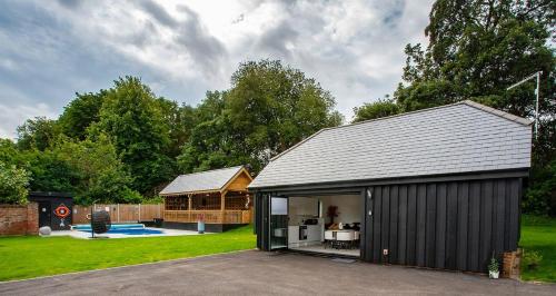 a large black shed in a yard with a backyard at Incredible summer winter 32c heated pool hot tub bar in Kent