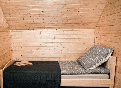 a bed in a cabin with a wooden wall at Górskie Chatki Krysi i Piotrka Perłowy in Stronie Śląskie