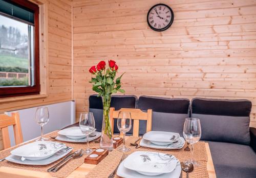 a table with plates and a vase with red roses at Górskie Chatki Krysi i Piotrka Perłowy in Stronie Śląskie