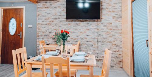 a wooden table with chairs and a television on a brick wall at Górskie Chatki Krysi i Piotrka Perłowy in Stronie Śląskie