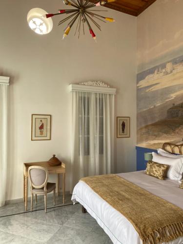 a bedroom with a bed and a desk and a chandelier at Dar Alice in Soûr