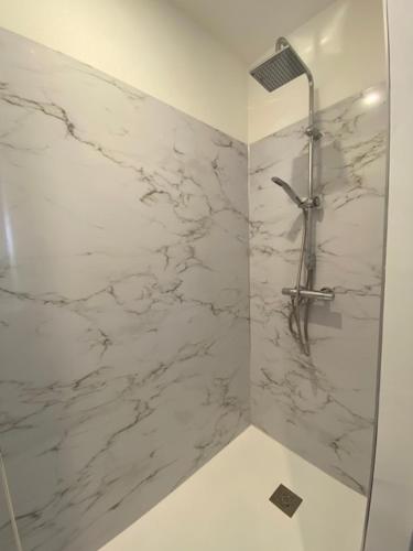 La salle de bains est pourvue d'une douche en marbre blanc. dans l'établissement Myaka Appartement Wood, à Cholet
