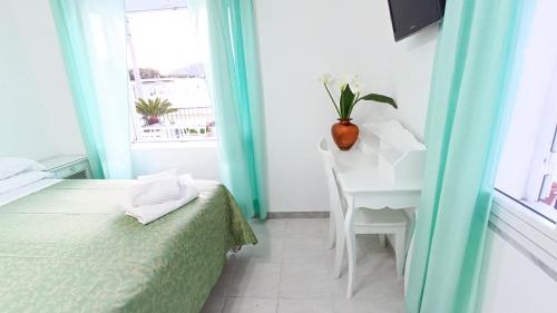 a bedroom with a bed and a desk and a window at Hotel Casa Nicola in Ischia